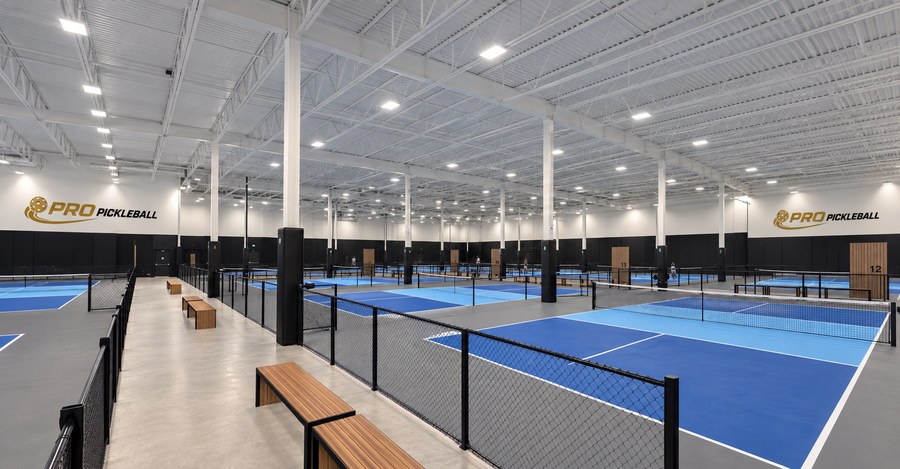 Vue intérieure des terrains Pro Pickleball sous un plafond blanc avec éclairage sportif